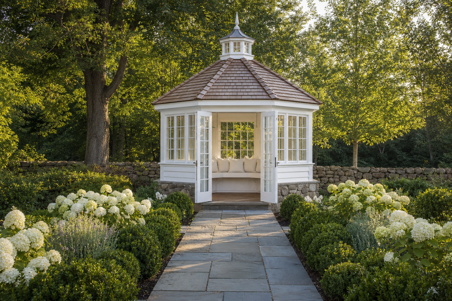 Octagonal garden pavilion with fieldstone base, white clapboard and French doors, cedar shingle roof with cupola, and bluestone path through hydrangea borders in Norwalk
