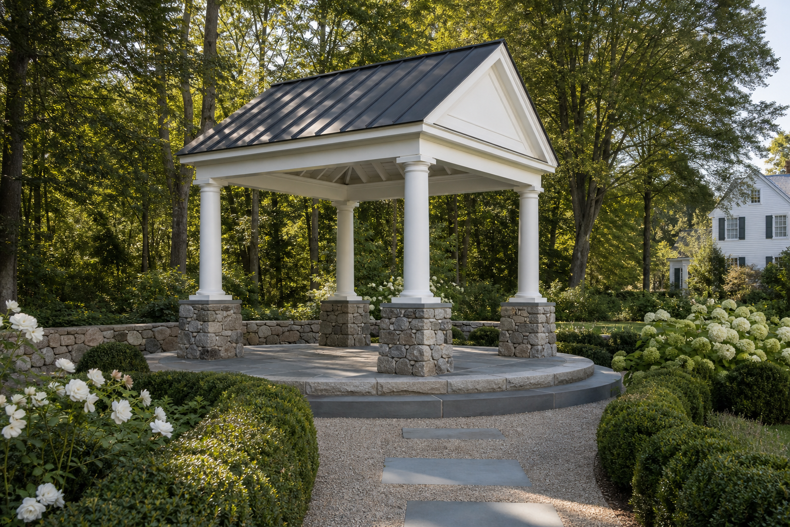 Colonial Revival garden temple pavilion with white columns on fieldstone pedestals, standing-seam metal pediment roof, and circular bluestone terrace in Norwalk